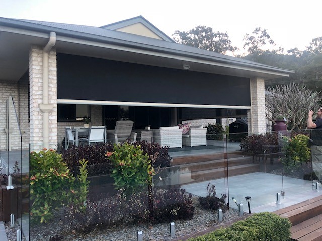 Motorised patio screen being lowered over an outdoor entertaining area